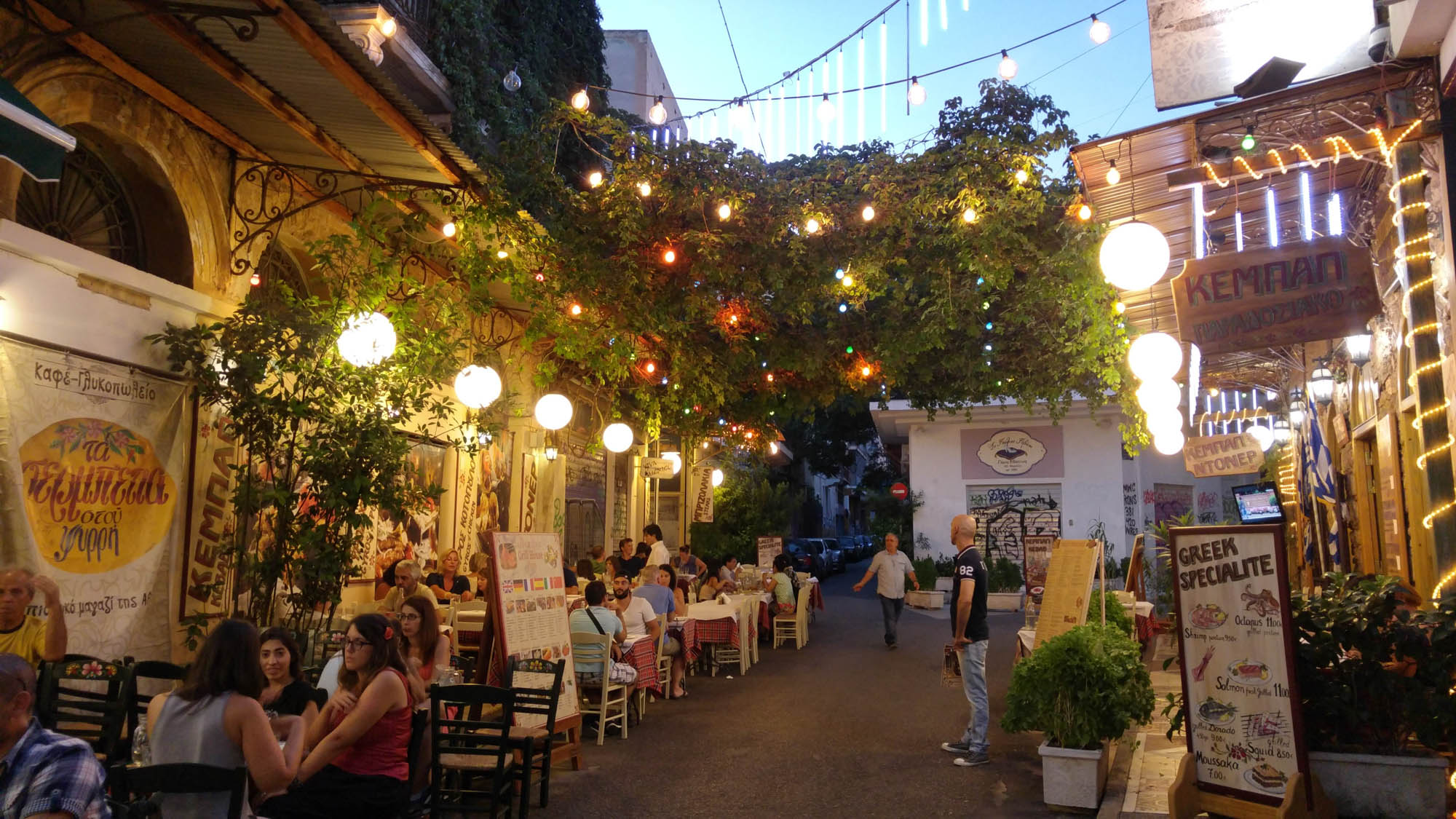 Grecy siedzący przy stolikach wieczorem w Atenach