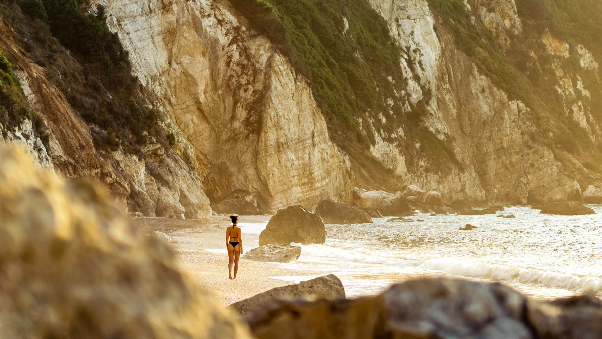 pusta plaża wśród skał, jedna dziewczyna na plaży, zdjęcie z oddali