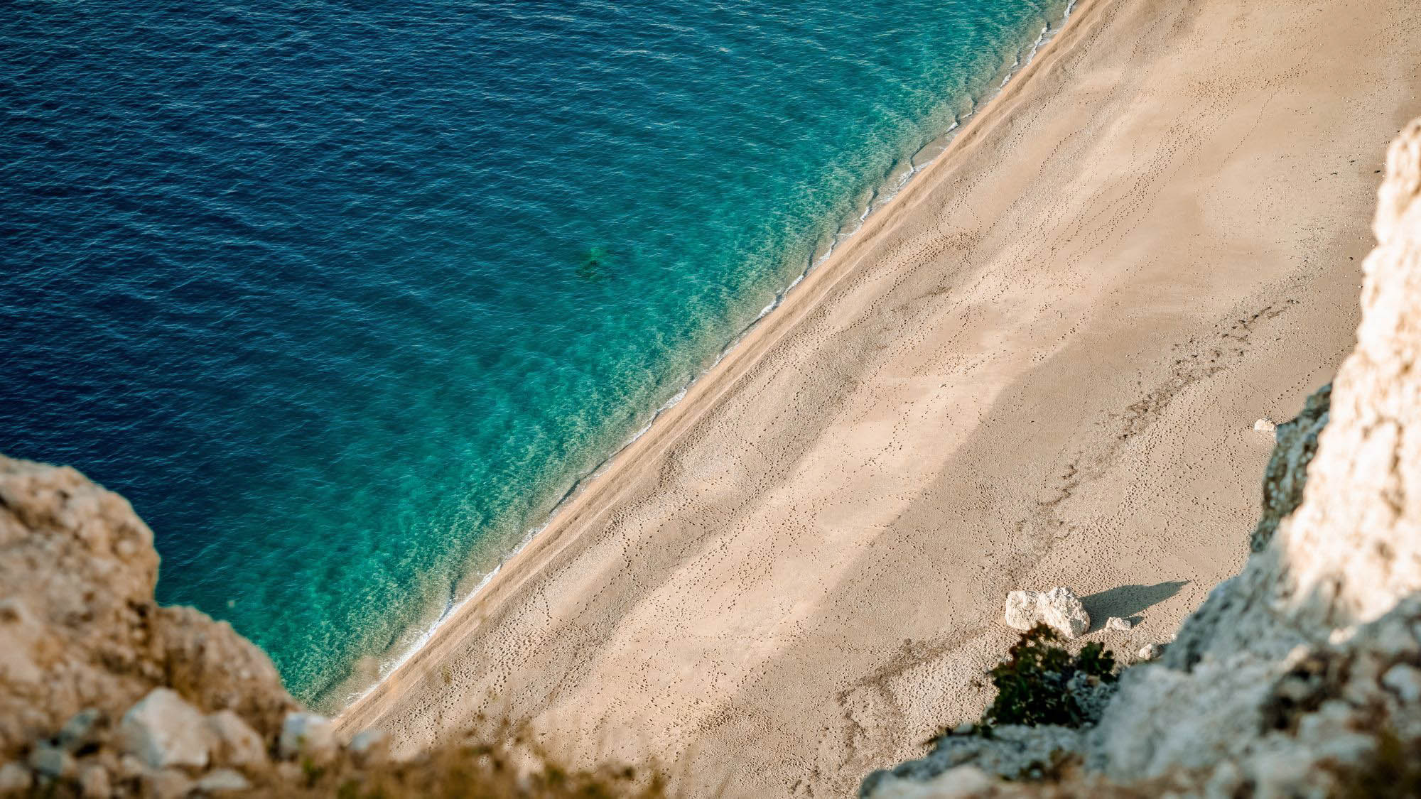 długa plaża z jasnym piaskiem i niebieskie morze, widok z góry