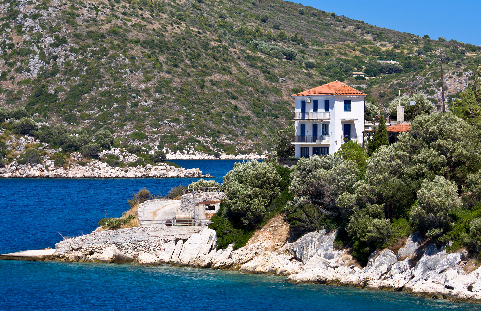 widok na skałę z typowym greckim domem na klifie