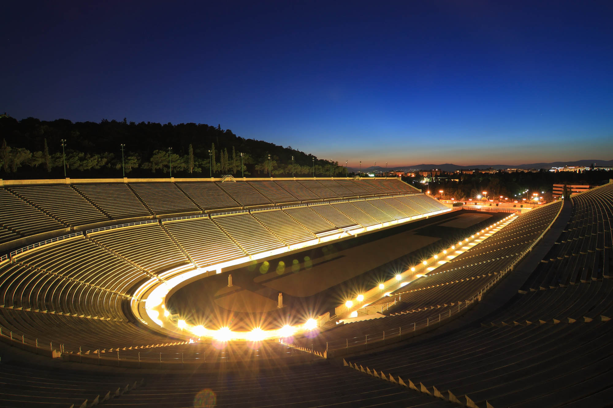 widok na oświetlony stadion a w tle zachodzące słońce