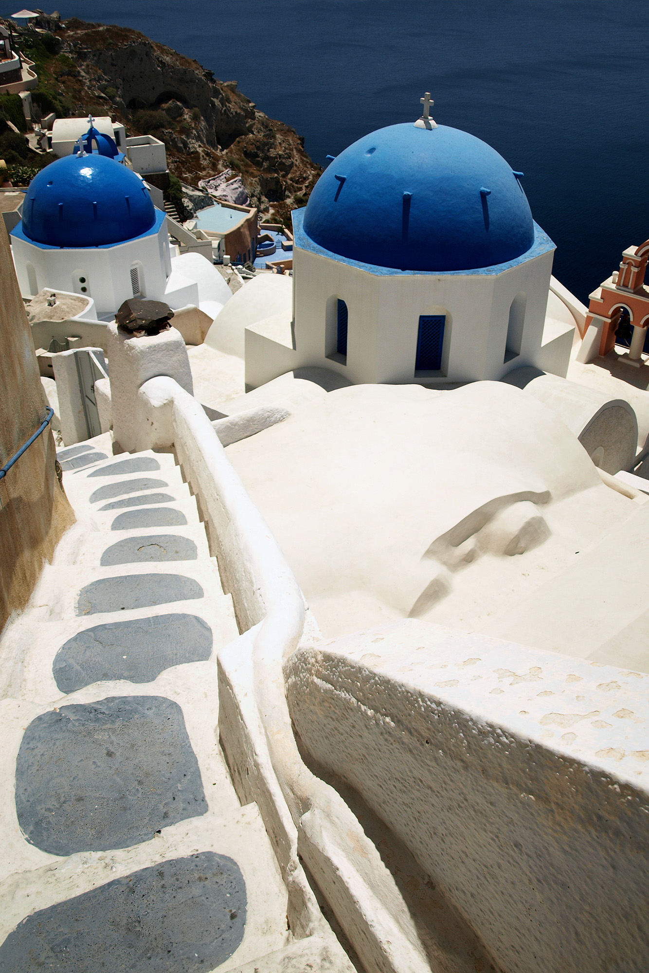 typowy widok z Santorini, niebiesko biała cerkiew na tle morza i białych domków