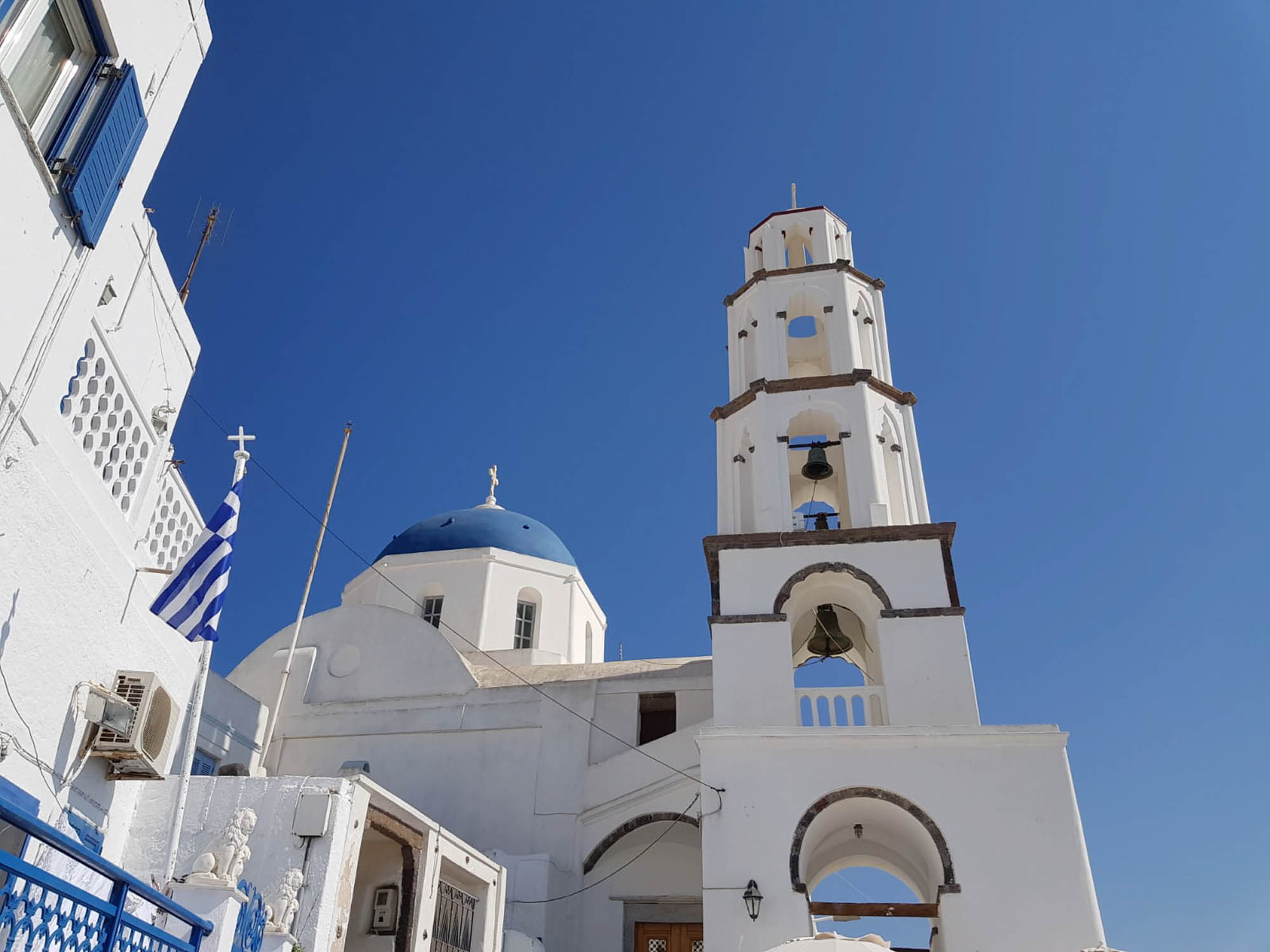pyrgos, widok na cerkiew i charakterystyczną biało niebieską dzwonnicę, niebieskie niebo nad santorini