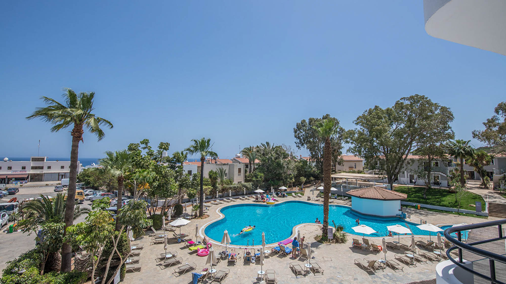 hotelowy basen z palmami, a w tle niebieskie niebo