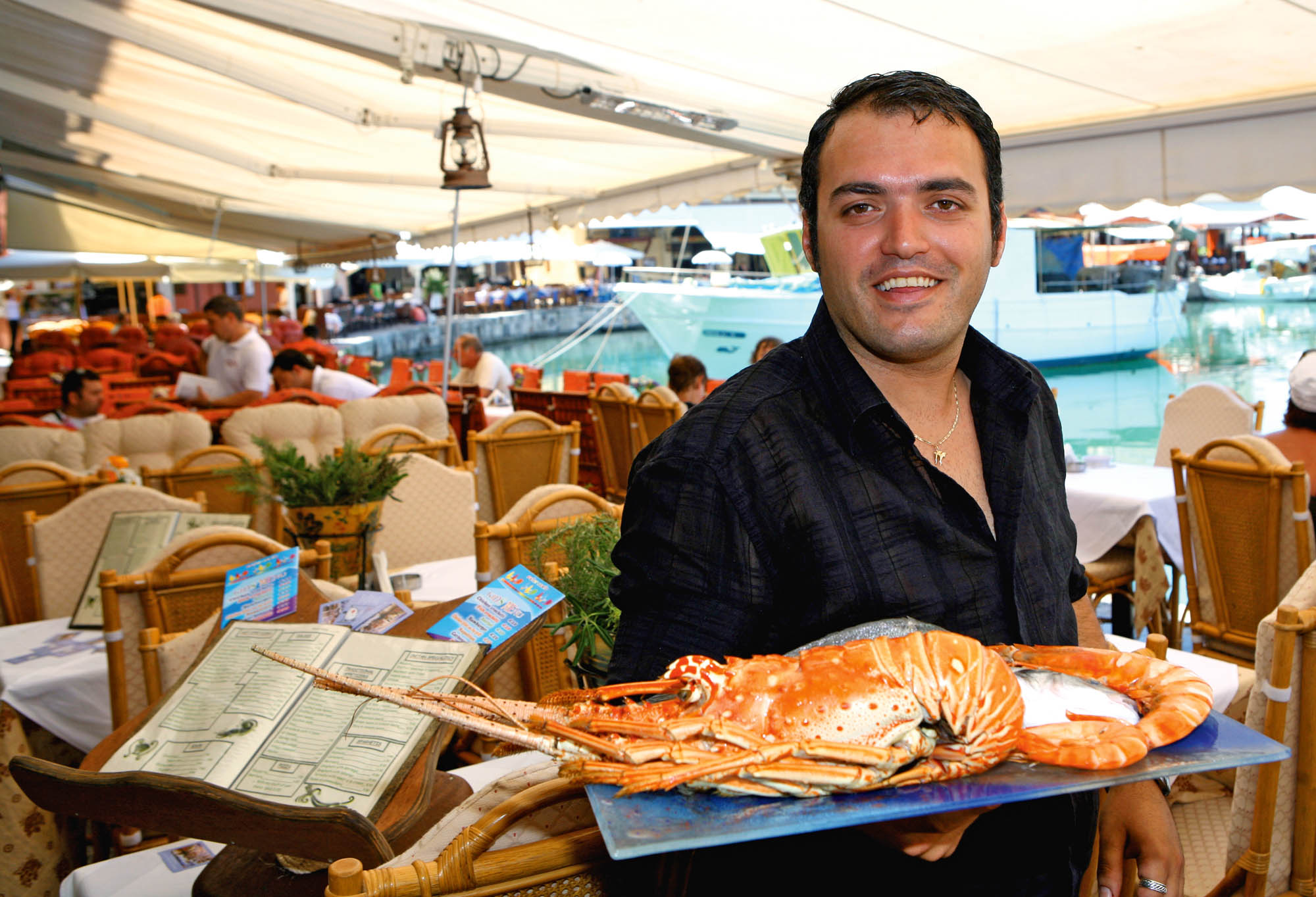człowiek podający owoce morza w tawernie, kelner z dużym talerzem, uśmiechnięty grek
