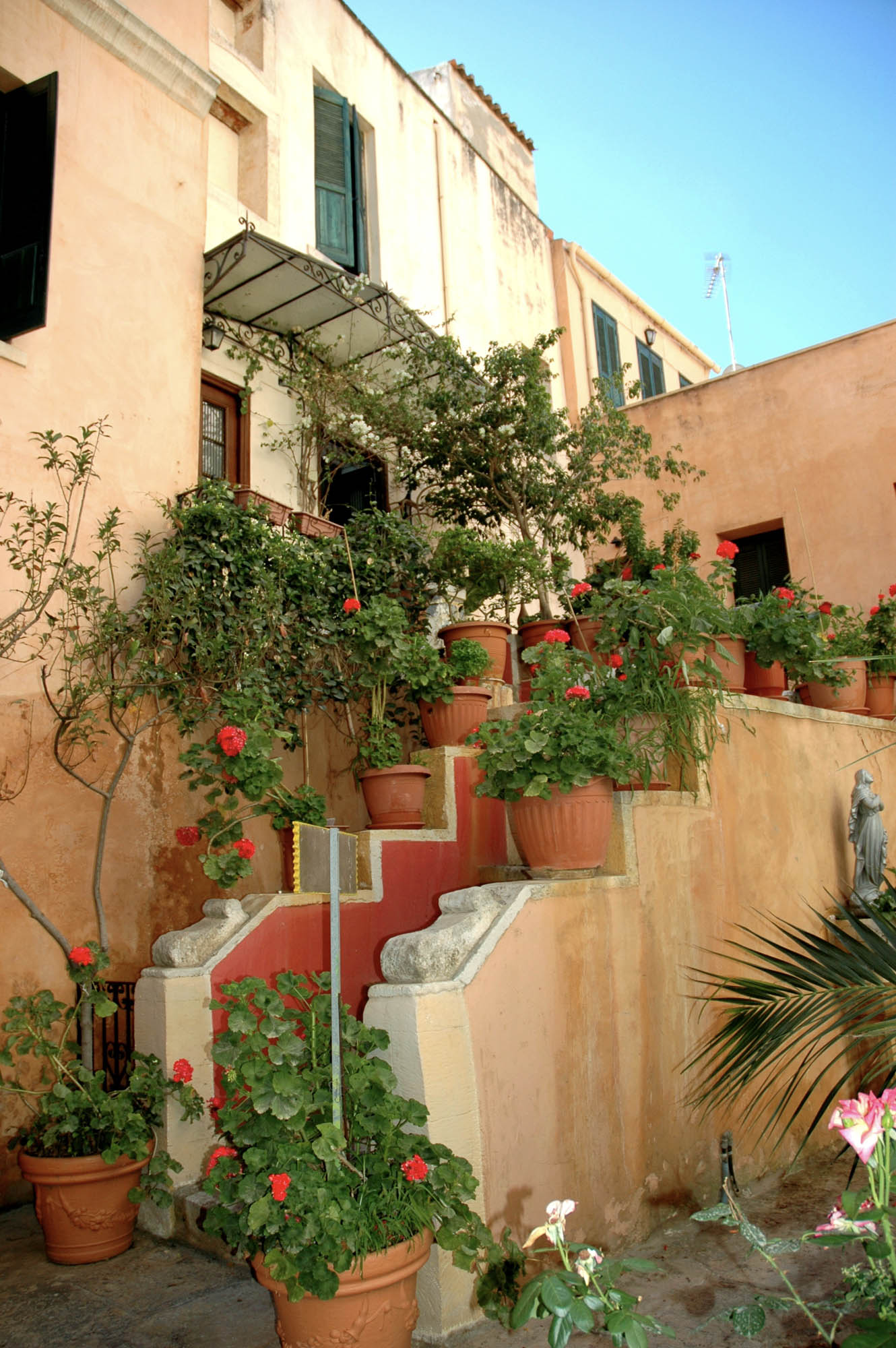 budynek w jednym z greckich miasteczek na krecie, donice z kwiatami na schodach