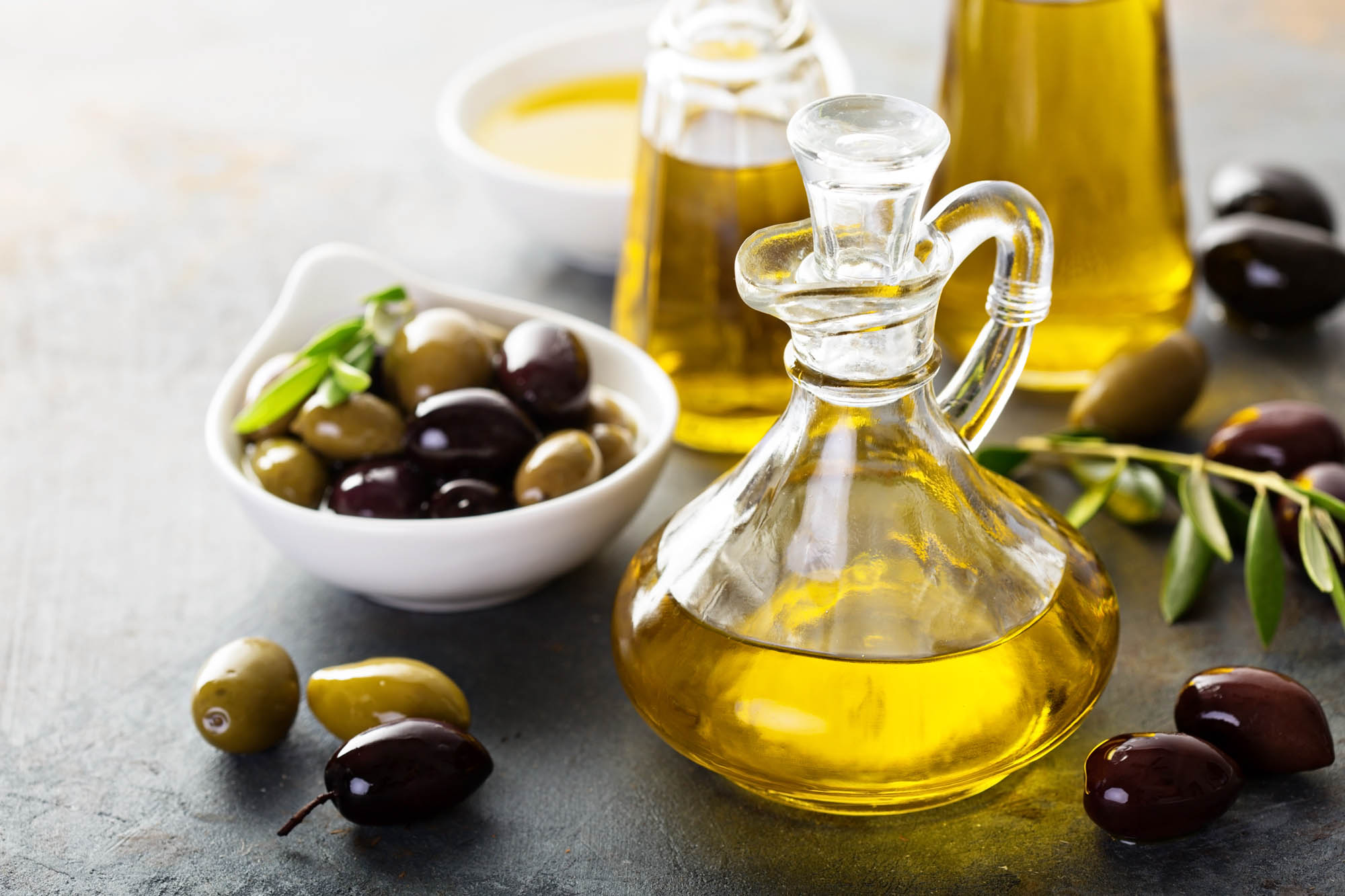 oliwa z oliwek w ładnej, ozdobnej buteleczka, a obok w miseczce leżą oliwki