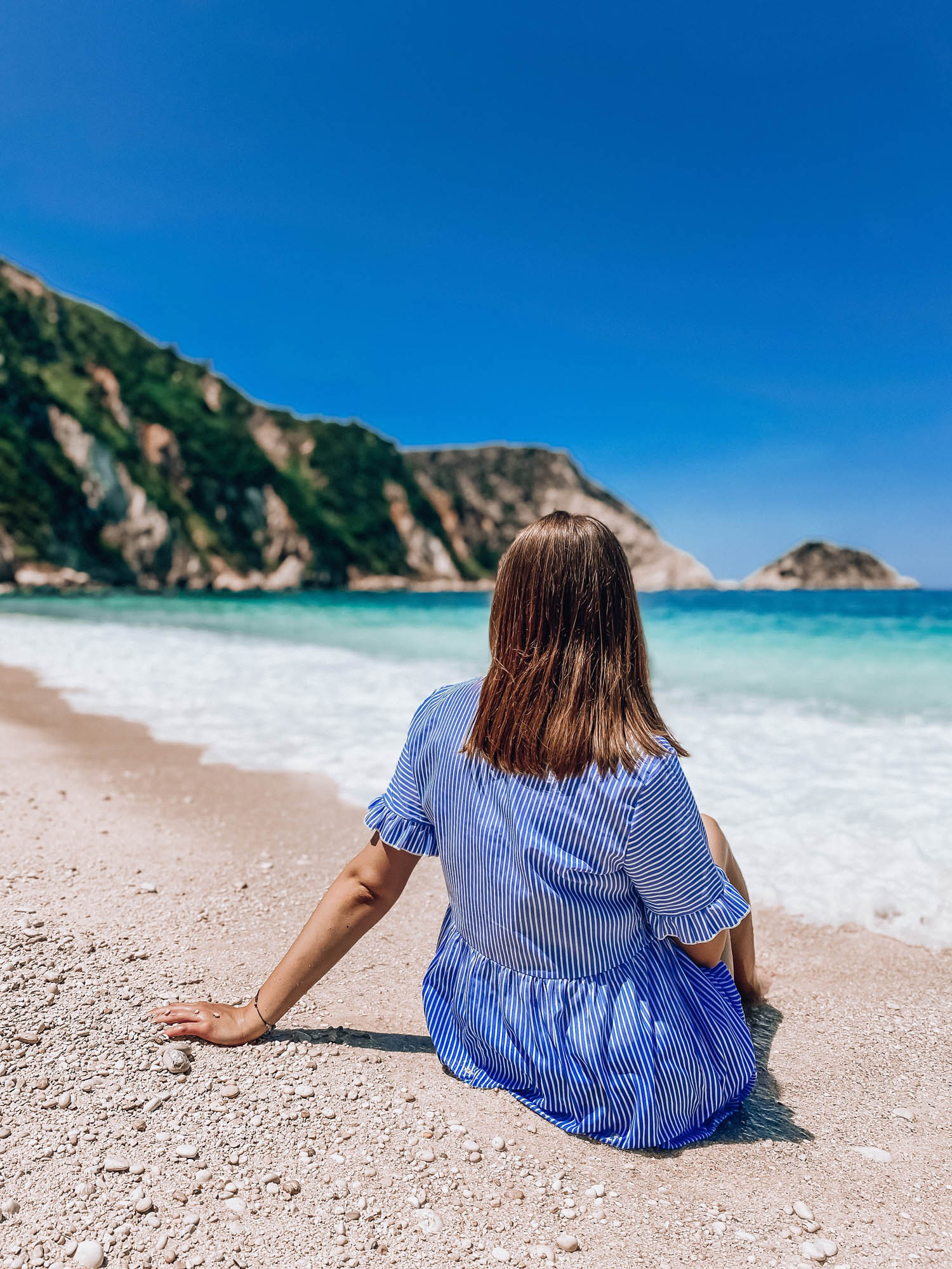 dziewczyna siedzi na plaży, plaża petani na kefalonii