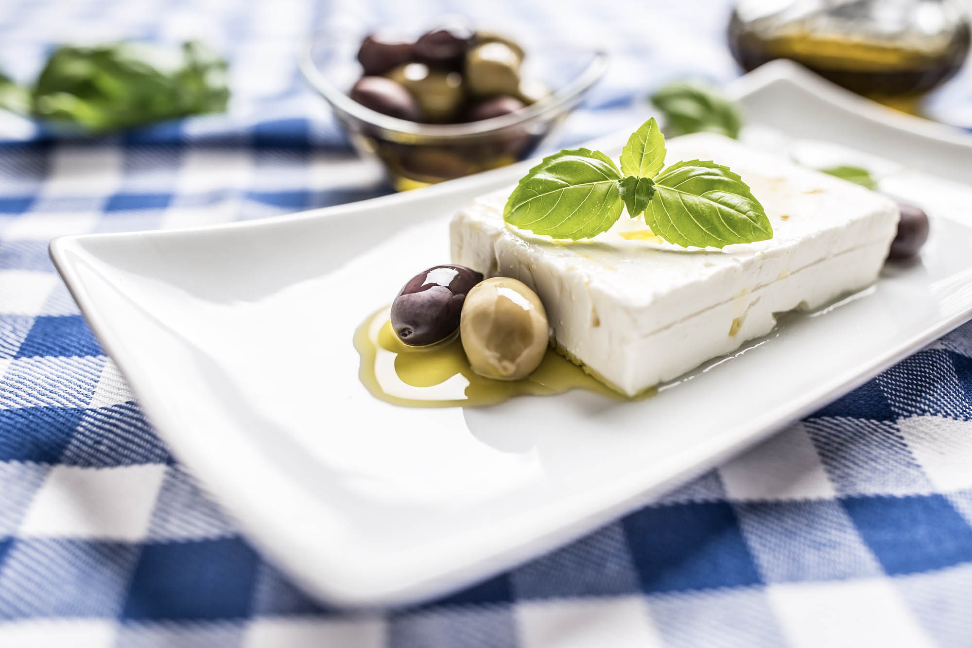 grecki ser feta podany na białym talerzyku z oliwkami