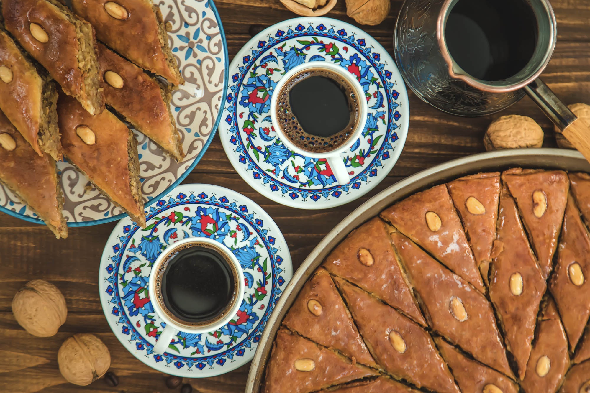 kawa w kolorowych filiżankach a obok pełne talerze baklavy, greckie rpzysmaki