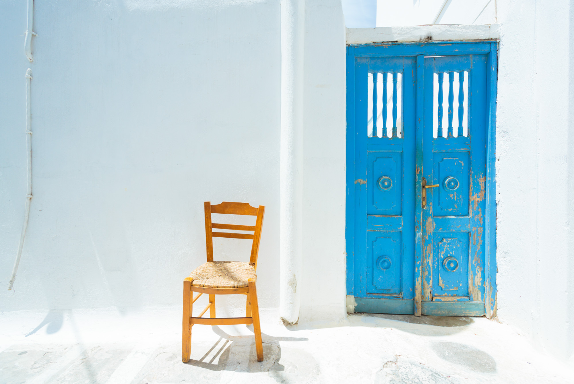 krzesło i niebieskie drzwi na tle białej ściany