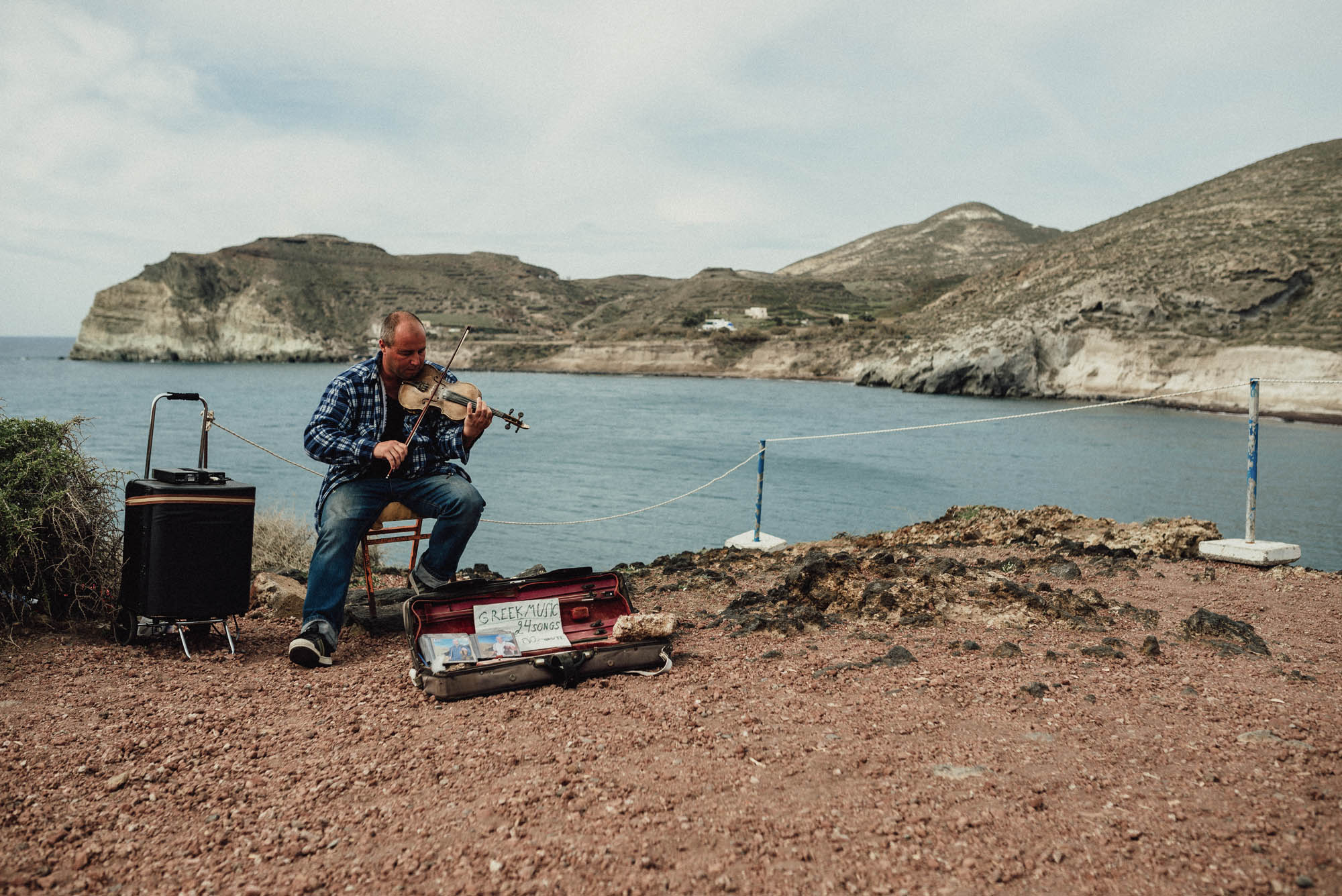 muzyk grające na instrumencie na brzegu morza, w tle widok na plaże i morze
