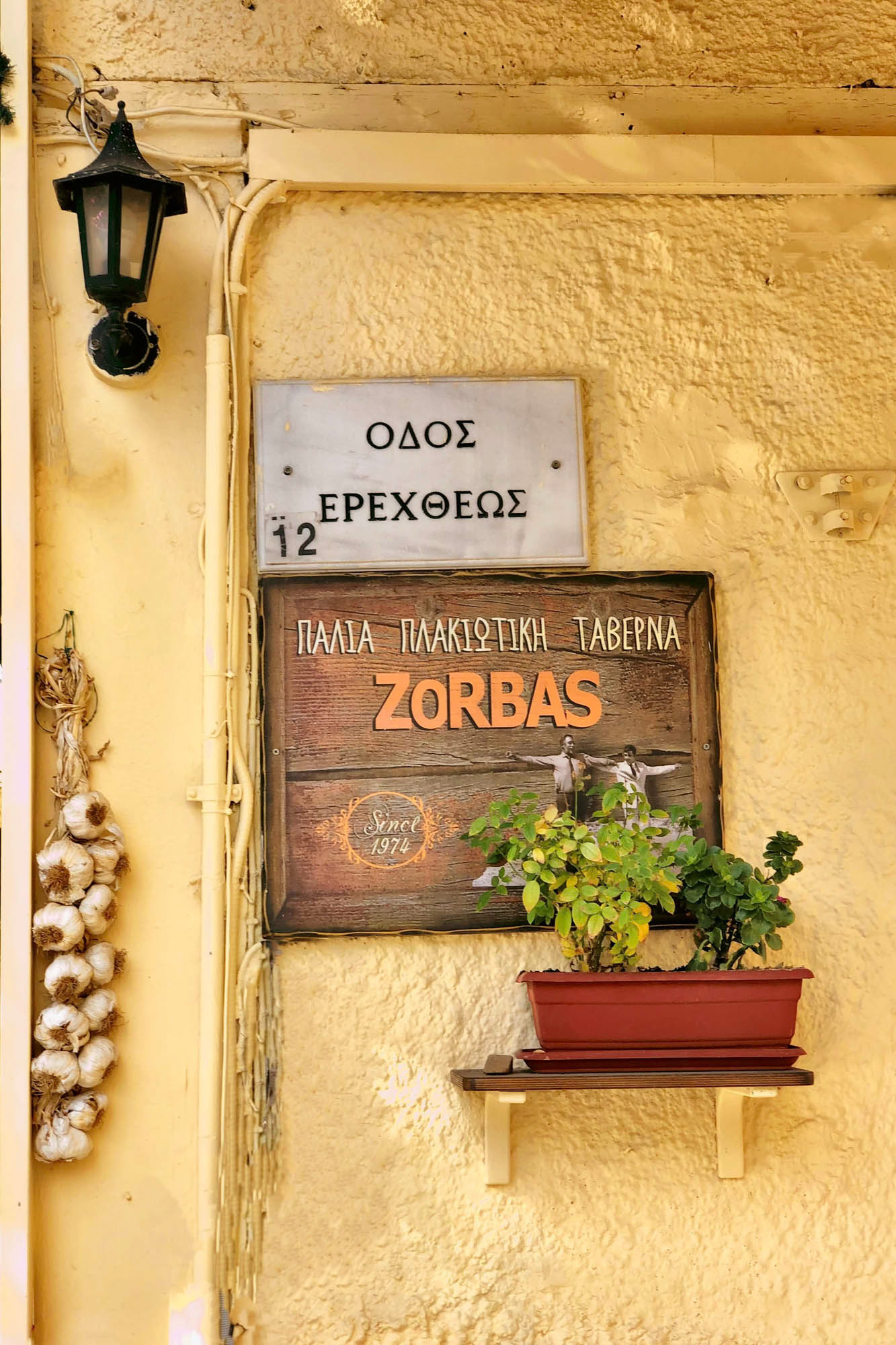 kafejka gdzies w grecji, nazwa na tabliczce z uroczym kwiatkiem