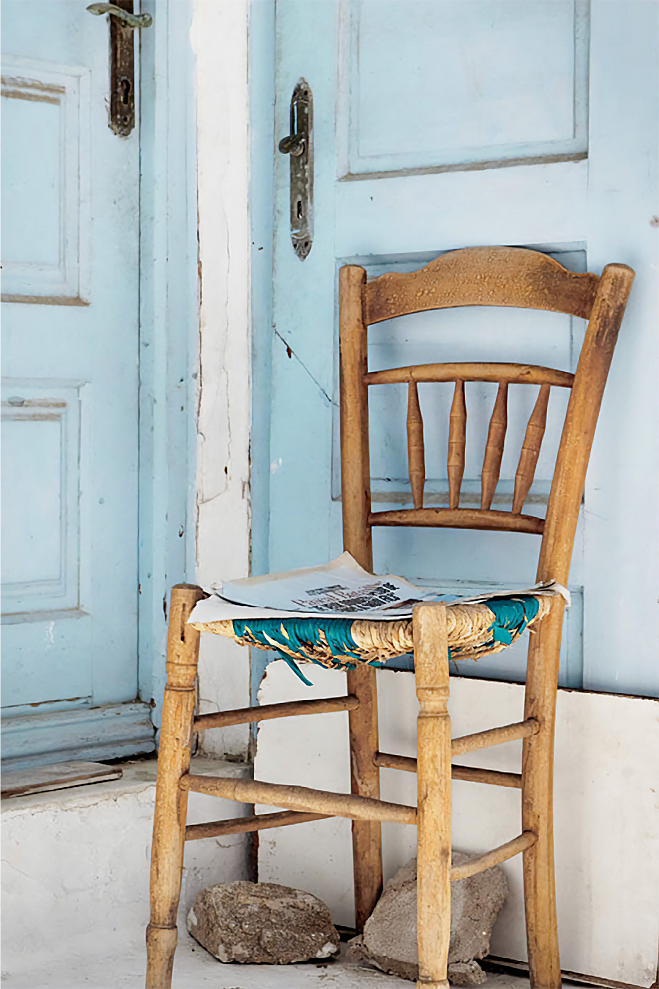 krzesełko stojące pod ścianą z niebieskimi drzwiami