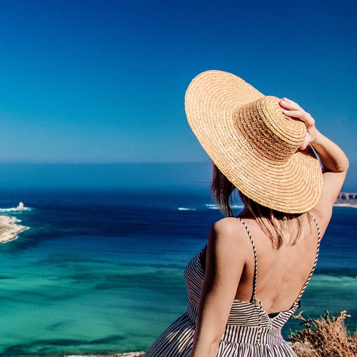 kobieta w kapeluszu patrzy na lazurowe morze
