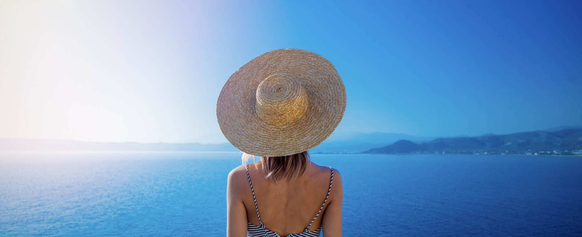 osoba w kapeluszu patrząca w dal na morze