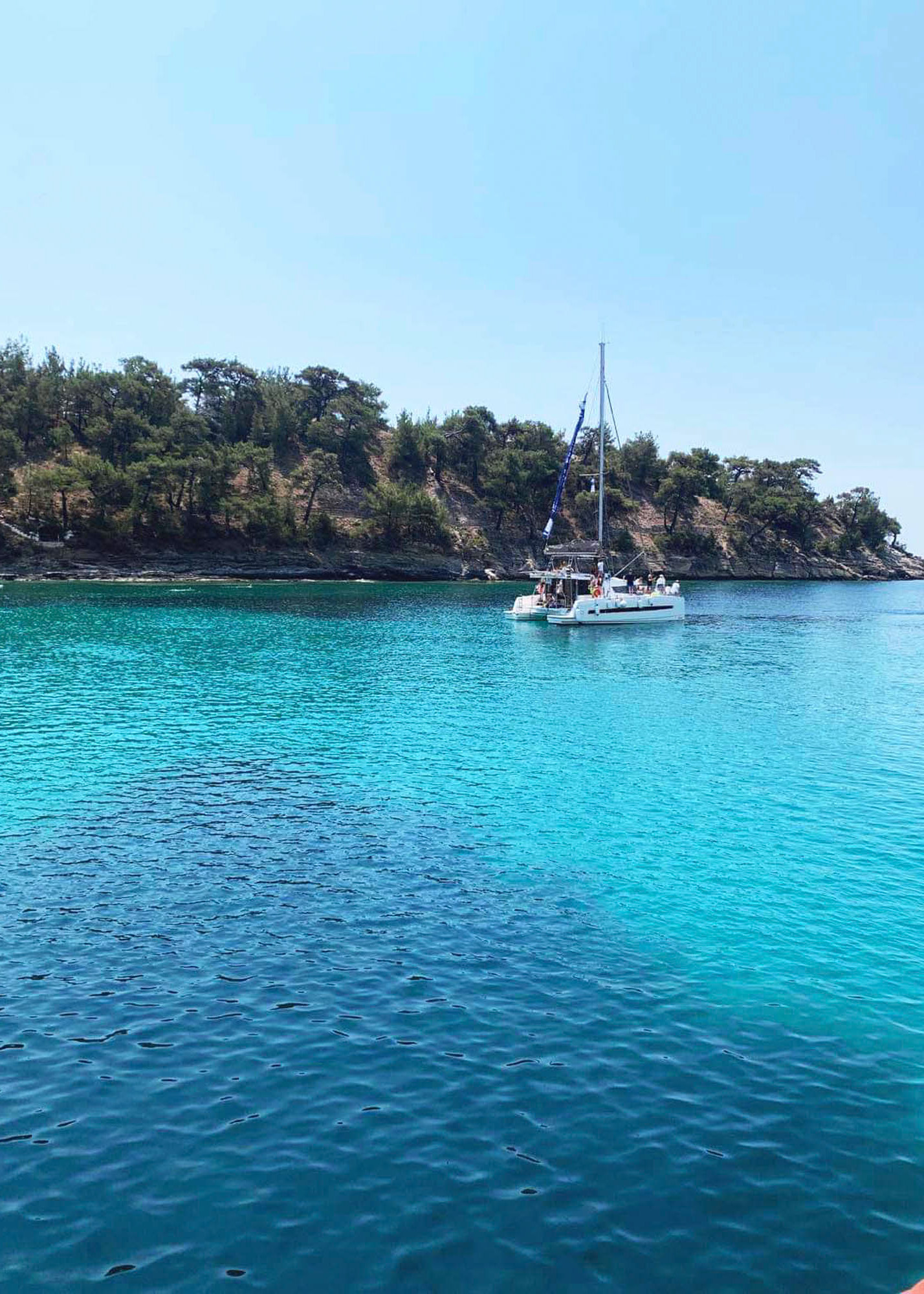 piękna lazyurowa woda tuż u wybrzeży wyspy thassos, w tle jacht, mała łódeczka, rajski widok
