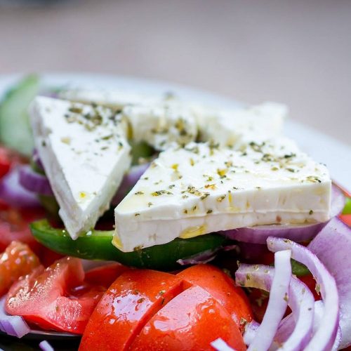 grecka sałatka z dużym kawałkiem sera na szczycie warzyw