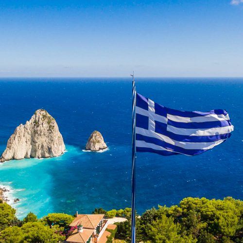 grecka flaga powiewa gdzieś na tle morza i nieba