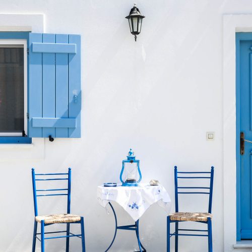 Grecja, stoliki i krzesełka, niebieskie okiennice, typowy grecki widok