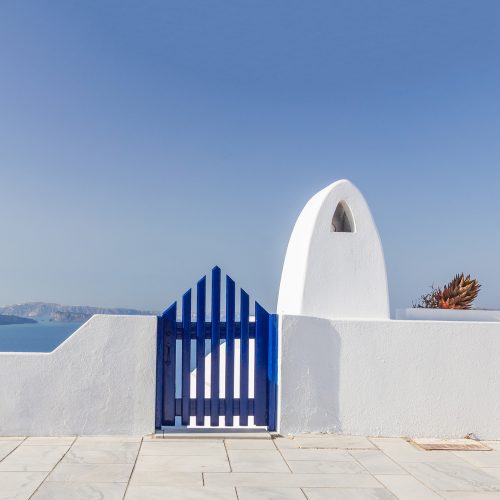 santorini, oia, widok na białą ścianę z niebieską furtką