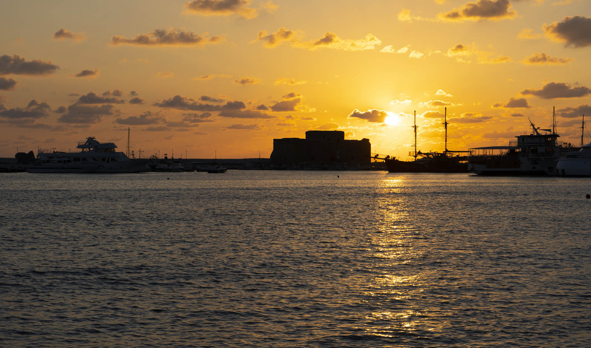 zachód słońca, widok na port pafos, zamek i łodzie