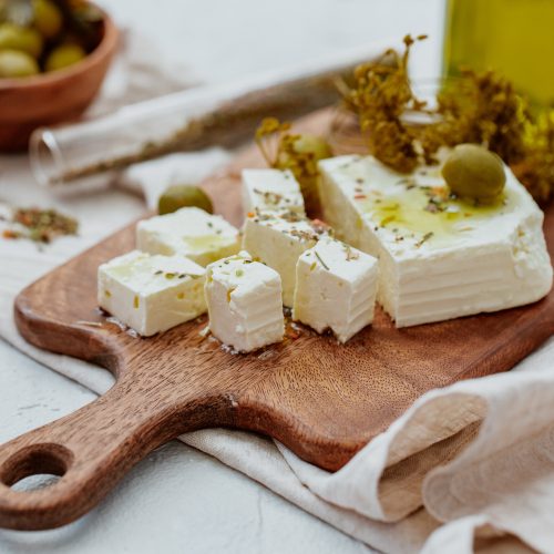 świeża feta grecka krojona na drewnianej desce, greckie smaki